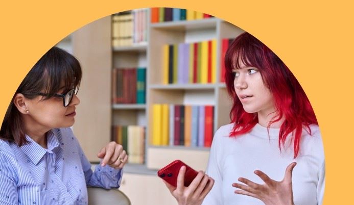 a female social prescriber listening to a teenager, who is holding a smartphone