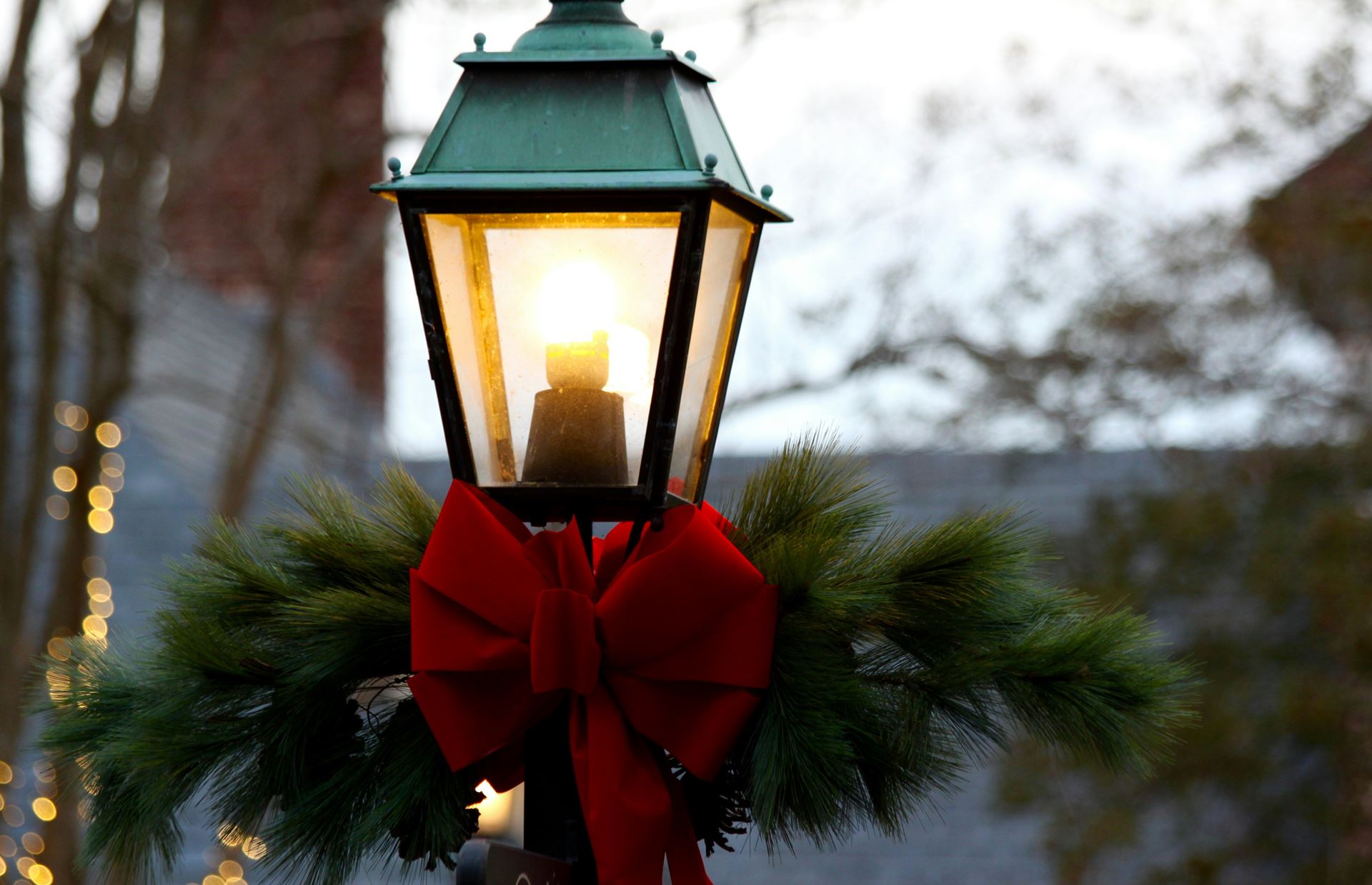 a gaslit streetlamp with a red bow tied on it