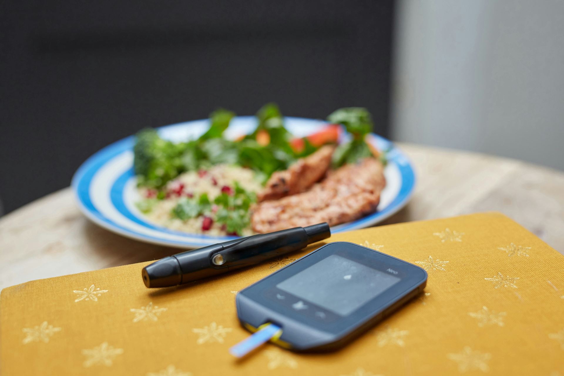 glucose monitoring eequipment on a table with a plat of healthy food